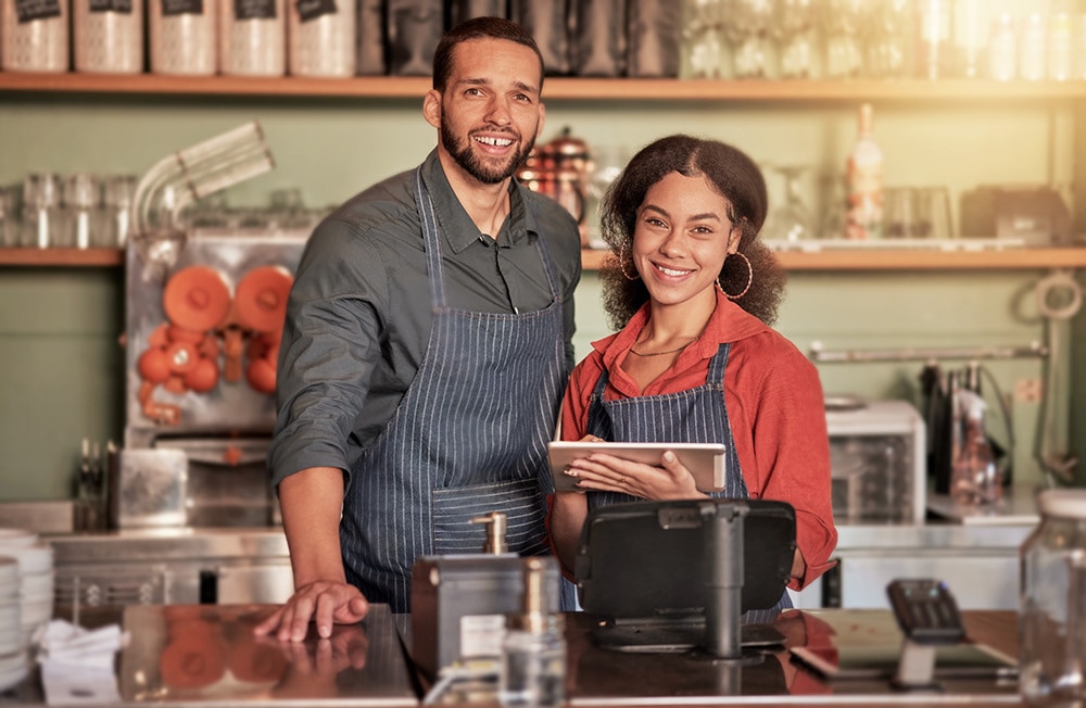 two business owners posing in front of their front desk